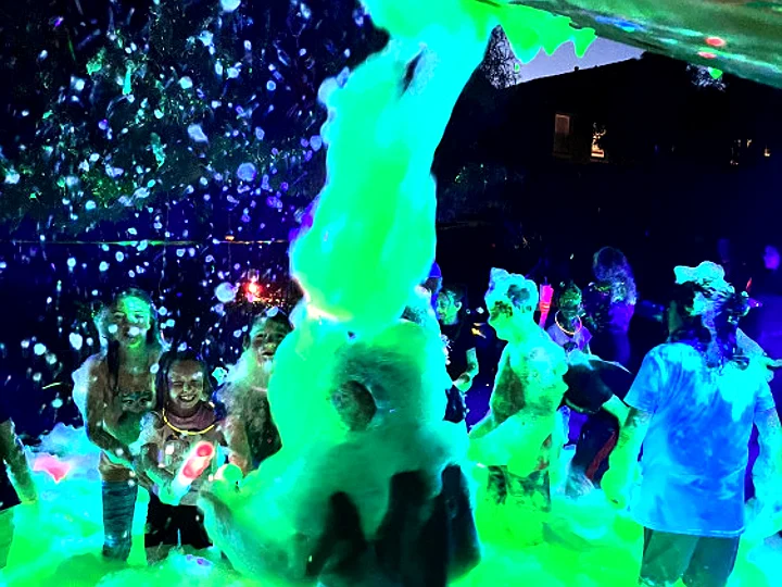 Kids dancing in glowing foam at night
